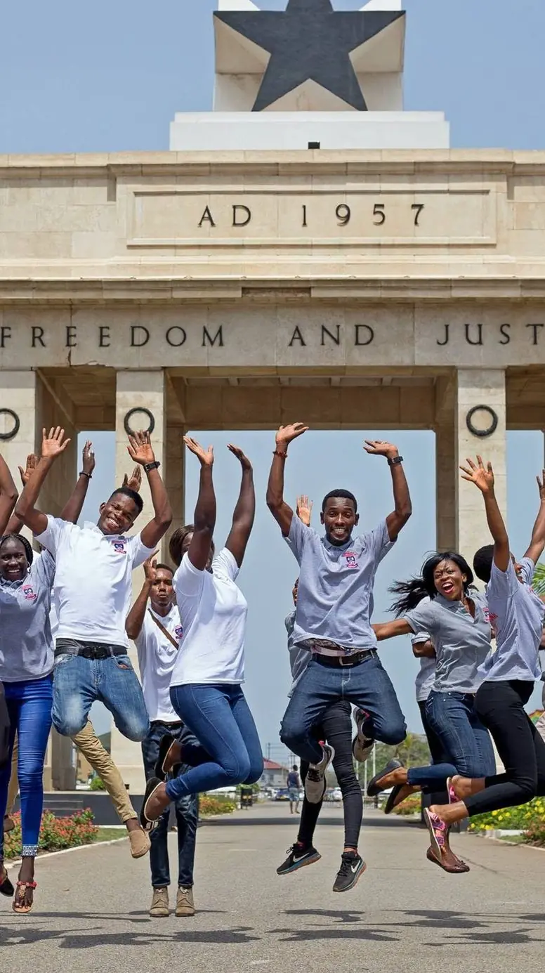 Étudiants d'IPI sautant de joie devant l'Arche de l'Indépendance à Accra, Ghana