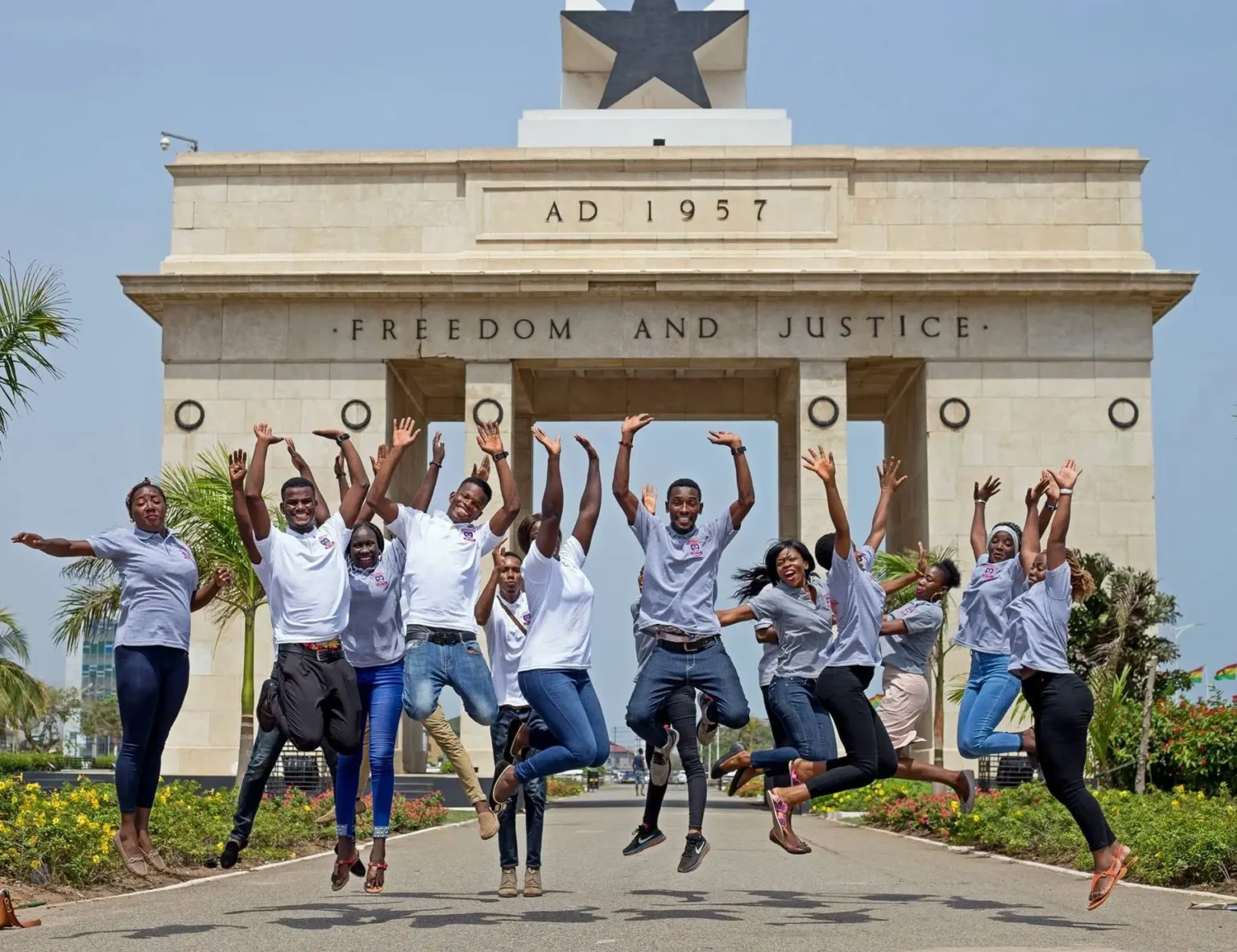 Étudiants d'IPI sautant de joie devant l'Arche de l'Indépendance à Accra, Ghana