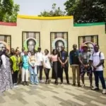 Étudiants d'IPI devant un mur de portraits historiques à Accra